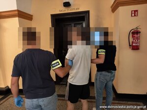 Dwaj policjanci prowadzą zatrzymanego.