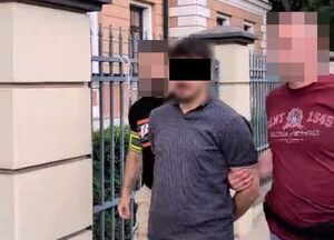 Dwaj funkcjonariusze prowadzą zatrzymanego.