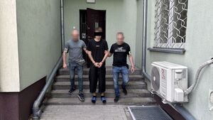 policjanci stoją na schodach z zatrzymanym.