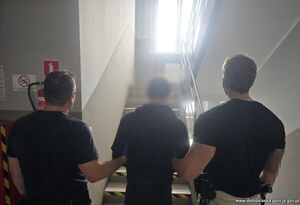 Dwaj policjanci prowadzą zatrzymanego.