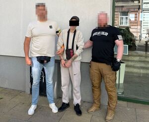 dwóch policjantów stoi z zatrzymanym.