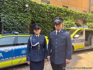 Umundurowani policjanci przed radiowozem.