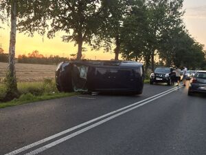 Miejsce wypadku. Na drodze przewrócony na bok bus. Za nim stoją auta osobowe.