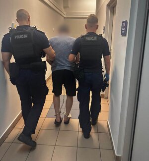 dwóch policjantów prowadzi zatrzymanego.