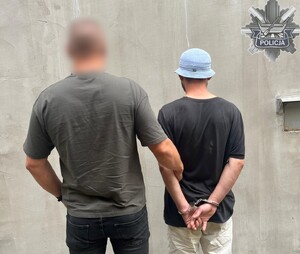 policjant stoi z zatrzymanym.