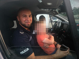 Policjant z dzieckiem w radiowozie.