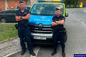 policjanci mł. asp. Paweł Skalij oraz sierż. Dariusz Kondratowicz stoją przed radiowozem.