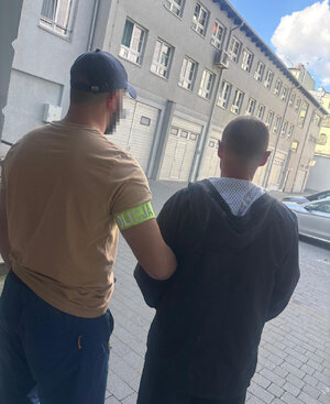 Policjant prowadzi zatrzymanego.