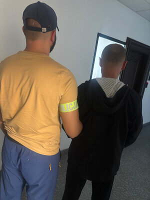Policjant prowadzi zatrzymanego.