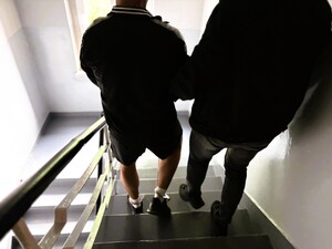 Policjant schodzi z zatrzymanym po schodach.