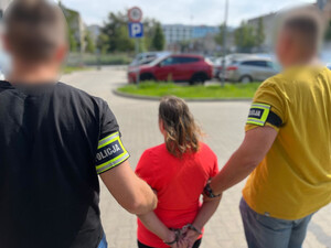 Policjanci prowadzą zatrzymaną kobietę