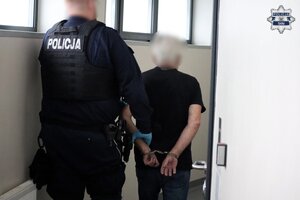 Policjant prowadzi zatrzymanego.