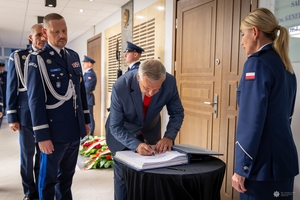 Sekretarz Stanu w Ministerstwie Spraw Wewnętrznych i Administracji Wiesław Szczepański wpisuje się do księgi pamięci. Obok stoi komendant główny Policji.