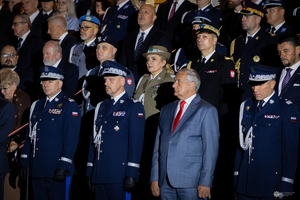 Uczestnicy uroczystości stoją na schodach wejściowych Komendy Głównej Policji.