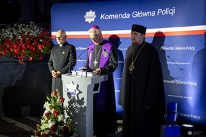Trzej duchowni stoją przy mównicy.