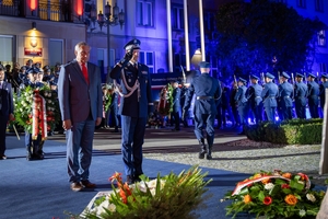 Sekretarz Stanu w Ministerstwie Spraw Wewnętrznych i Administracji Wiesław Szczepański, Komendant Główny Policji gen. insp. Marek Boroń oddają hołd poległym policjantom przed obeliskiem na terenie Komendy Głównej Policji. W tle uczestnicy uroczystości stojący przed budynkiem KGP.