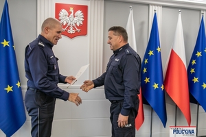 I Zastępca Komendanta Głównego Policji ściska dłoń funkcjonariuszowi gratulując.