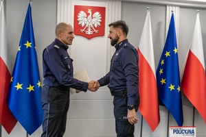 I Zastępca Komendanta Głównego Policji ściska dłoń funkcjonariuszowi gratulując.