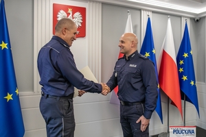 I Zastępca Komendanta Głównego Policji ściska dłoń funkcjonariuszowi gratulując.