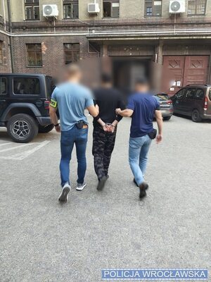 policjanci prowadzą zatrzymanego.