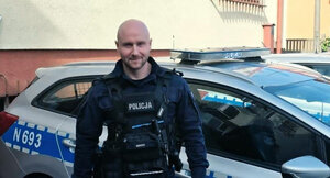 policjant stoi przed radiowozem.