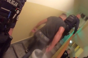 Policjanci wchodzą po schodach w bloku.
