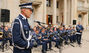 Przemawia Zastępca Komendanta Głównego Policji, w tle muzycy policyjnej orkiestry.