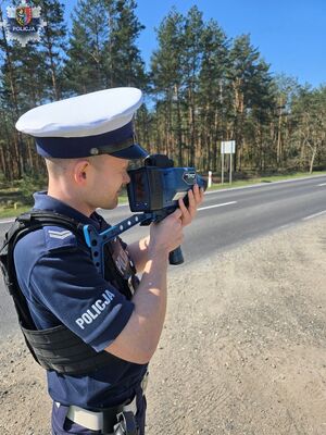 Policjant ruchu drogowego z ręcznym fotoradarem podczas kontroli drogowej.
