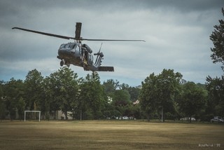 Pogodny dzień. Policyjny Black Hawk z kontrterrorystami ląduje na płcie trawiastego boiska piłkarskiego.
