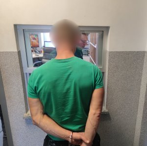 zatrzymany stojący tyłem z kajdankami na rękach