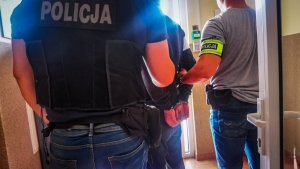 dwóch policjantów trzyma zatrzymanego