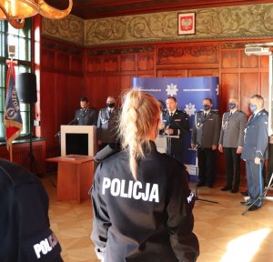 Ślubowanie nowych policjantów, policjanci wypowiadają słowa roty z podniesiona do góry dłonią