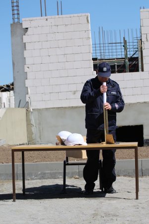 Komendant Powiatowy Policji w Sławnie wkłada akt erekcyjny i pamiątki do tuby