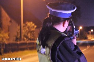 Policjantka ruchu drogowego kontroluje prędkość pojazdów nocą.