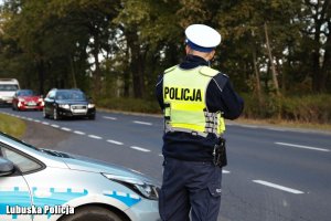 Policjant ruchu drogowego kontroluje prędkość jadących pojazdów.