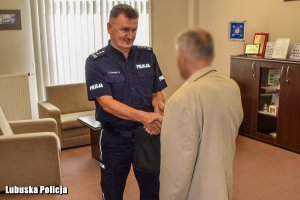 Policjant podaje rękę mężczyźnie w swoim gabinecie.