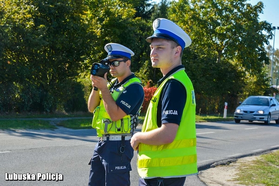 Policjanci drogówki kontrolujący prędkość przy drodze.