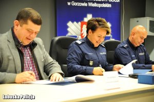 Mężczyzna oraz policjanci podpisują dokumenty.