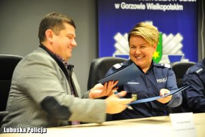 Mężczyzna i policjantka wymieniają się dokumentami.