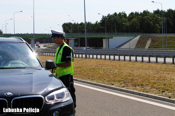 Policjanci przy kontrolowanym pojeździe na drodze.