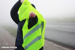 Mężczyzna ubiera kamizelkę odblakową