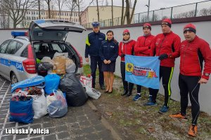 policjanci i sportowcy stoją przy radiowozie z paczkami