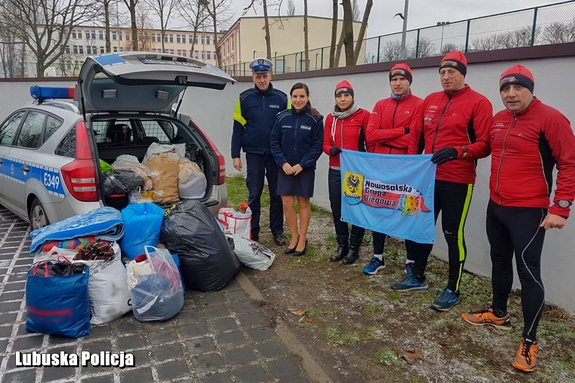 policjanci i sportowcy stoją przy radiowozie z paczkami