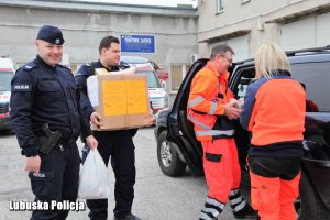 policjanci i ratownicy medyczni pakują paczki do samochodu