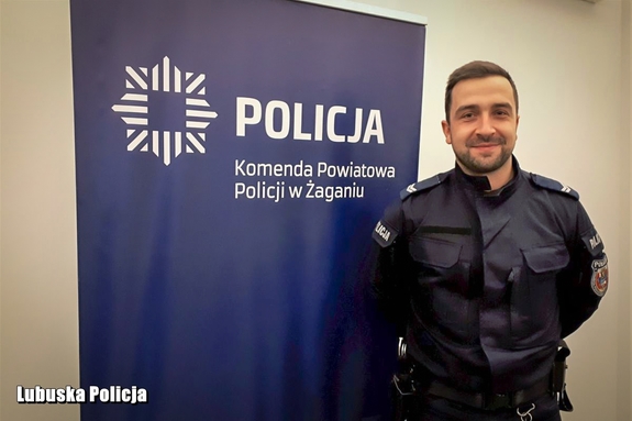 Policjant pozujący do zdjęcia na tle ściany.