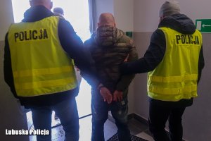 Policjanci prowadzą zatrzymanego mężczyznę.