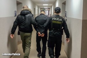 Policjanci z zatrzymanym mężczyzną w pomieszczeniu komendy.