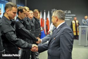 Mężczyzna składa gratulacje policjantom stojącym w szeregu.