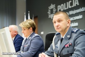 Policjanci siedzący za stołem prezydialnym.