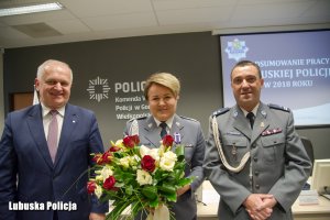 Mężczyzna, a obok niego policjanci z kwiatami pozujący do zdjęcia.